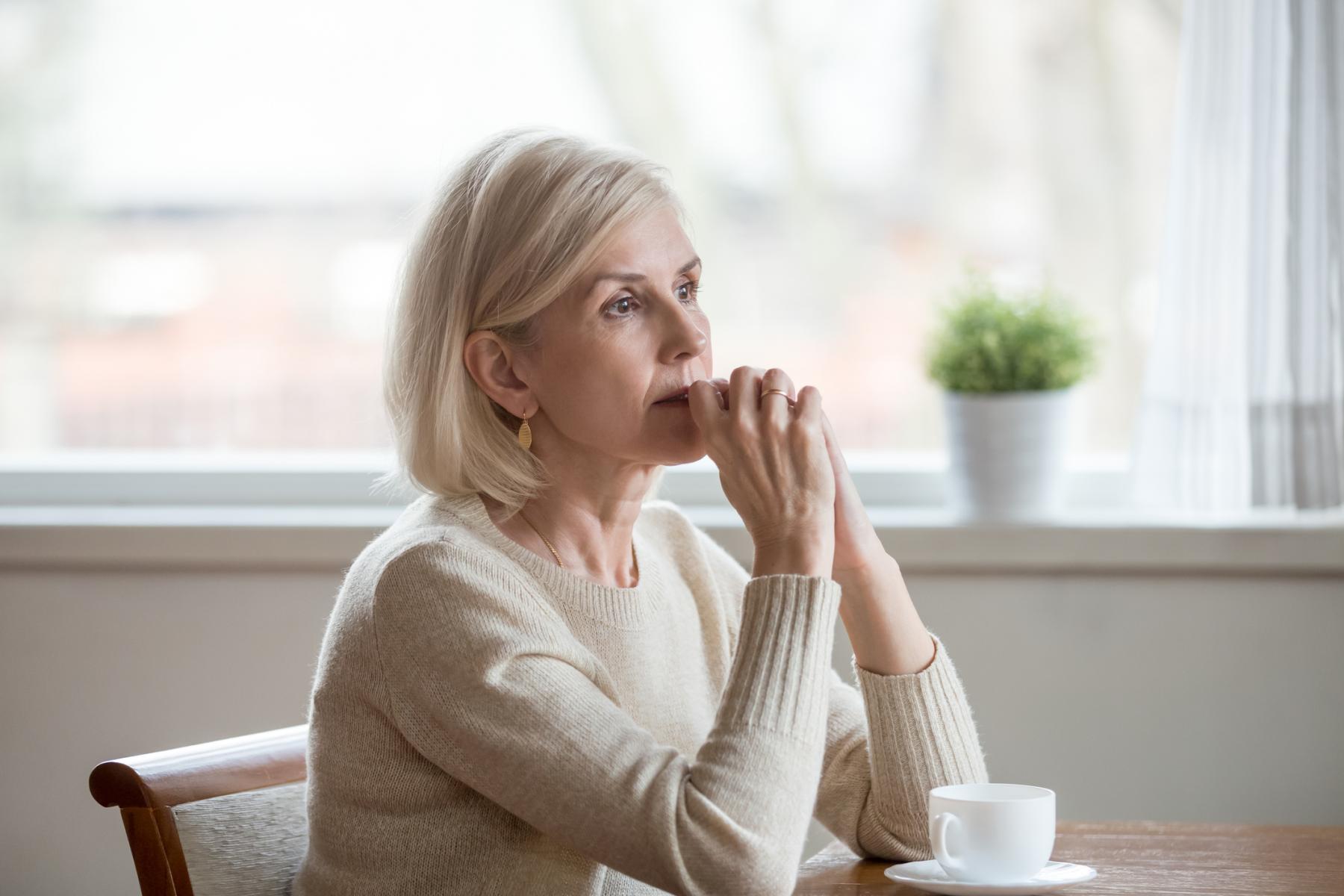 thoughtful woman sitting with cup of tea